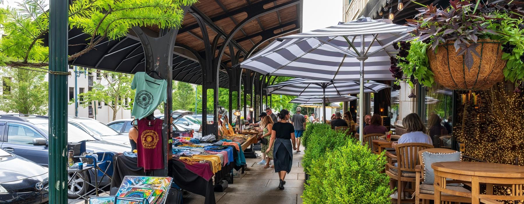 a sidewalk with tables and chairs and umbrellas